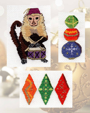 Gothic Ornaments Cross Stitch Pattern includes three designs.  A monkey drummer with purple fez and drumsticks crossed, three decorated ornament balls stacked in green, orange and purple, three decorated diamonds all highlighted in gold thread.  Design by Wendy Christine.  For sale at www.raspberrylanecrafts.com An American Company